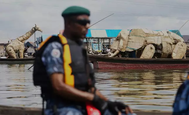 Puppeteers move cardboard animals in canoes at the Makoko Slum in Lagos Nigeria, Saturday, April 19, 2025, as part of "The Herds," a moving theatre performance that started its journey from the Democratic Republic of the Congo to the Arctic Circle in a bid to bring attention to the climate crisis. (AP Photo/Sunday Alamba)