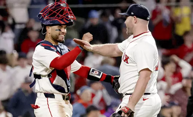 Boston Red Sox catcher Carlos Narváez, left and Boston Red Sox pitcher Liam Hendriks, right, celebrate their win over the Seattle Mariners at the end of a baseball game, Tuesday, April 22, 2025, in Boston. (AP Photo/Mark Stockwell)