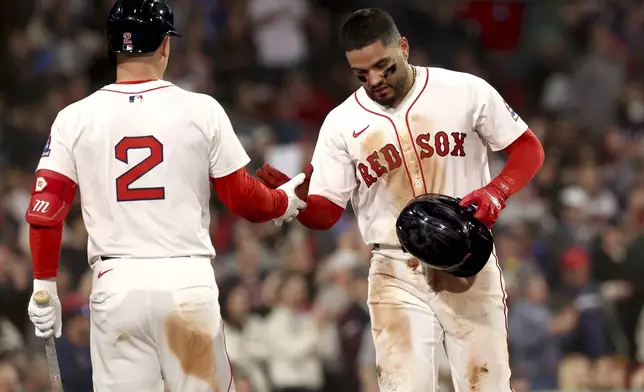Boston Red Sox's Carlos Narváez, right, high-fives teammate Alex Bregman (2) after scoring during the seventh inning of a baseball game against the Seattle Mariners, Tuesday, April 22, 2025, in Boston. (AP Photo/Mark Stockwell)