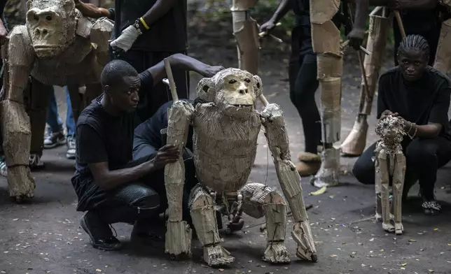 Puppeteers move cardboard animals through DRC's capital Kinshasa's botanical gardens Thursday, April 10, 2025, the first steps of "The Herds", a moving theatre performance that will travel from the Democratic Republic of the Congo to the Arctic Circle in a bid to bring attention to the climate crisis. (AP Photo/Samy Ntumba Shambuyi)
