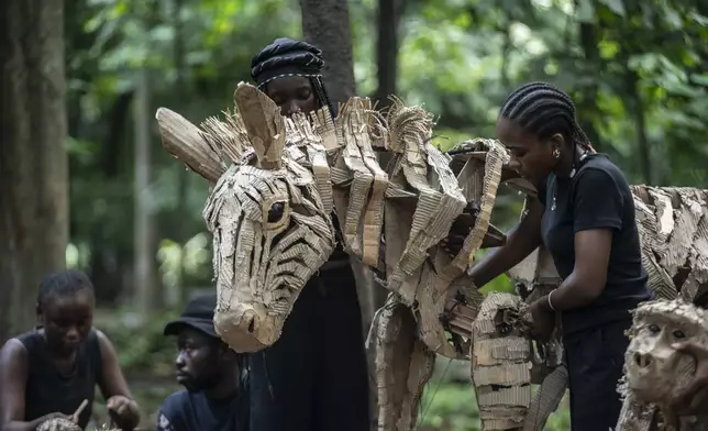 Puppeteers move cardboard animals through DRC's capital Kinshasa's botanical gardens Thursday, April 10, 2025, the first steps of "The Herds", a moving theatre performance that will travel from the Democratic Republic of the Congo to the Arctic Circle in a bid to bring attention to the climate crisis. (AP Photo/Samy Ntumba Shambuyi)