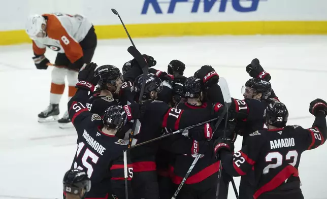 Philadelphia Flyers defenseman Cam York (8) skates past the Ottawa Senators as they celebrate their NHL hockey game overtime win in Ottawa, Sunday, April 13, 2025. (Adrian Wyld /The Canadian Press via AP)