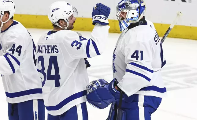 Toronto Maple Leafs center Auston Matthews (34) and goaltender Anthony Stolarz (41) celebrate a their team's victory following the third period of an NHL hockey game against the Buffalo Sabres, Tuesday, April 15, 2025, in Buffalo, N.Y. (AP Photo/Jeffrey T. Barnes)