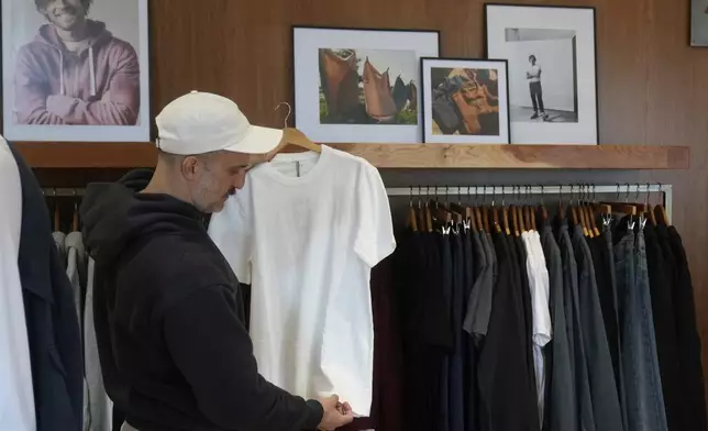Javid Moghaddasnia, Director of Customer Engagement, holds up an American Giant shirt while being interviewed at the company's showroom in San Francisco, Thursday, April 17, 2025. (AP Photo/Jeff Chiu)