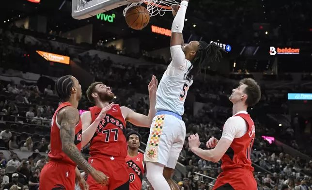 San Antonio Spurs guard Stephon Castle (5) dunks against Toronto Raptors' forward Jamison Battle (77) during the first half of an NBA basketball game, Sunday, April 13, 2025, in San Antonio. (AP Photo/Darren Abate)