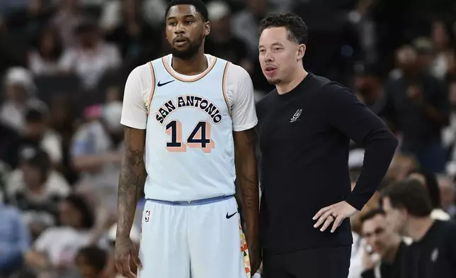 San Antonio Spurs acting head coach Mitch Johnson, right, speaks with Spurs guard Blake Wesley during the first half of their NBA basketball game against the Toronto Raptors, Sunday, April 13, 2025, in San Antonio. (AP Photo/Darren Abate)