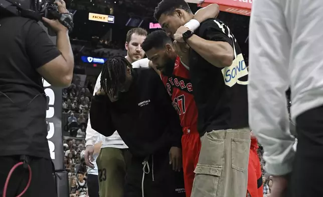 Toronto Raptors forward Garrett Temple (17) is helped off of the court after suffering an injury in the first half of an NBA basketball game against the San Antonio Spurs, Sunday, April 13, 2025, in San Antonio. (AP Photo/Darren Abate)