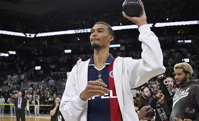 San Antonio Spurs forward Victor Wembanyama throws novelty basketballs to fans after an NBA basketball game against the Toronto Raptors, Sunday, April 13, 2025, in San Antonio. (AP Photo/Darren Abate)