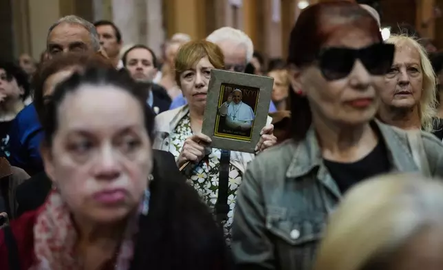A woman holds a photo of the late Pope Francis during an inter-religious prayer service in honor of the late pontiff at the Cathedral in Buenos Aires, Argentina, Tuesday, April 22, 2025. (AP Photo/Rodrigo Abd)