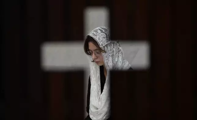 Photographed through the door of a confessional, a person prays during Mass in honor of Pope Francis, following the Vatican's announcement of his death, at the Cathedral in Brasilia, Brazil, Monday, April 21, 2025. (AP Photo/Eraldo Peres)