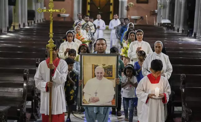 Christians arrive with a portrait of Pope Francis for a prayer ceremony at the Cathedral Church of the Resurrection, in Lahore, Pakistan Monday, April 21, 2025, following the announcement by the Vatican of the death of Pope Francis. (AP Photo/K.M. Chaudary)