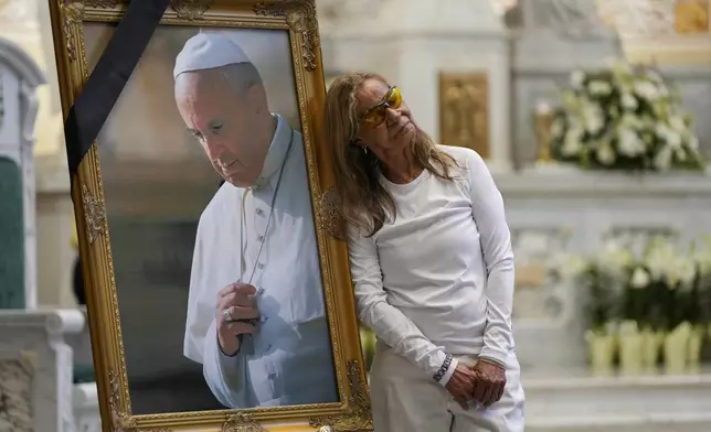 Maureen Boyd leans against a portrait of the late Pope Francis after a mass at the Cathedral of Incarnation, Wednesday, April 23, 2025, in Nashville, Tenn. (AP Photo/George Walker IV)