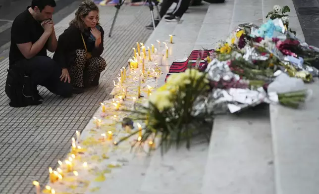 People pray in front of candles for the late Pope Francis on the grand staircase of the Cathedral in Buenos Aires, Argentina, Tuesday, April 22, 2025. (AP Photo/Rodrigo Abd)