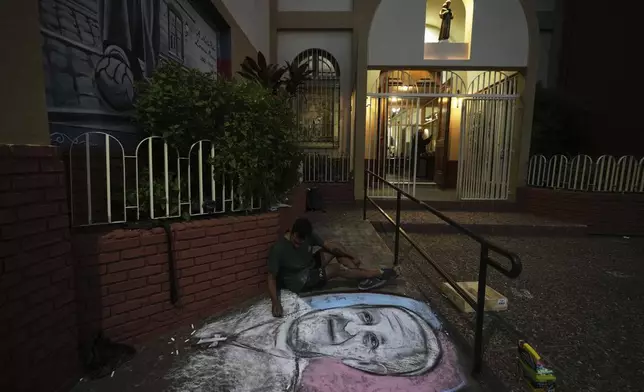 An artist paints an image of the late Pope Francis outside San Antonio parish before a Mass by fans of San Lorenzo soccer club, of which the pontiff was a lifelong supporter, in Buenos Aires, Argentina, Wednesday, April 23, 2025. (AP Photo/Natacha Pisarenko)