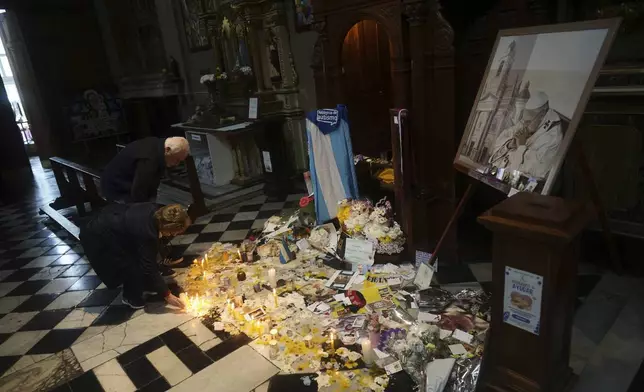 A woman lights a candle by the confessional at the Basilica de San Jose de Flores where the future Pope Francis, known as Jorge Bergoglio, first realized his calling to become a priest at age 17, in the Flores neighborhood where he grew up in Buenos Aires, Argentina, Thursday, April 24, 2025. (AP Photo/Natacha Pisarenko)