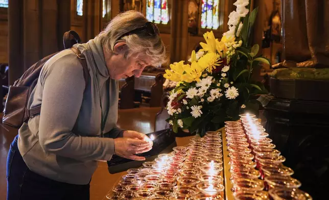 Suzanne Jessep lights a candle at Sydney's St Mary's Cathedral following the death of Pope Francis, Australia, Tuesday, April 22, 2025. (AP Photo/Rick Rycroft)