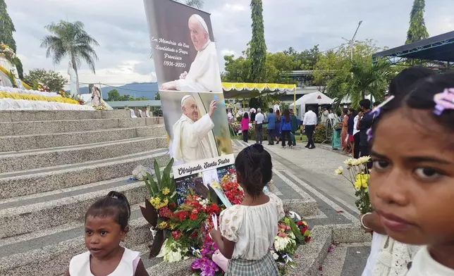 Devotees lay flowers near the banner of the late Pope Francis in Dili, East Timor, Wednesday, April 23, 2025. (AP Photo/Suzana Cardoso)