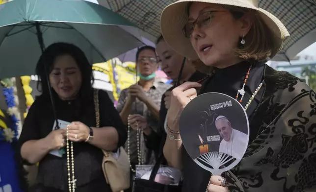 Devotees pray for the late Pope Francis as they wait for their turn to be allowed in to the Apostolic Nunciature to offer their condolences, in Jakarta, Indonesia, Wednesday, April 23, 2025.(AP Photo/Tatan Syuflana)
