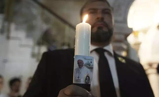 Issa Kassissieh holds a candle during a Mass led by Latin Patriarch Pierbattista Pizzaballa, the top Catholic clergyman in the Holy Land, in remembrance of Pope Francis at the Church of the Holy Sepulcher, the site where according to tradition Jesus was crucified and buried, in the Old City of Jerusalem, Wednesday, April 23, 2025. (AP Photo/Mahmoud Illean)