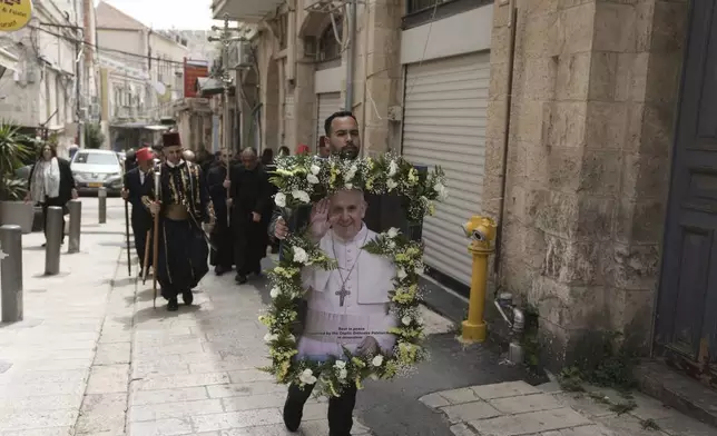 A man walks in procession with a picture of the late Pope Francis after a Mass led by Latin Patriarch Pierbattista Pizzaballa, the top Catholic clergyman in the Holy Land, in the Old City of Jerusalem, Wednesday, April 23, 2025. (AP Photo/Mahmoud Illean)