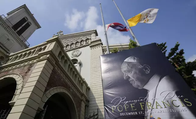 The Philippine flag, left, and Vatican flag are half-staff beside a portrait of the late Pope Francis at the Cubao Cathedral in Quezon city, Philippines Wednesday, April 23, 2025. (AP Photo/Aaron Favila)