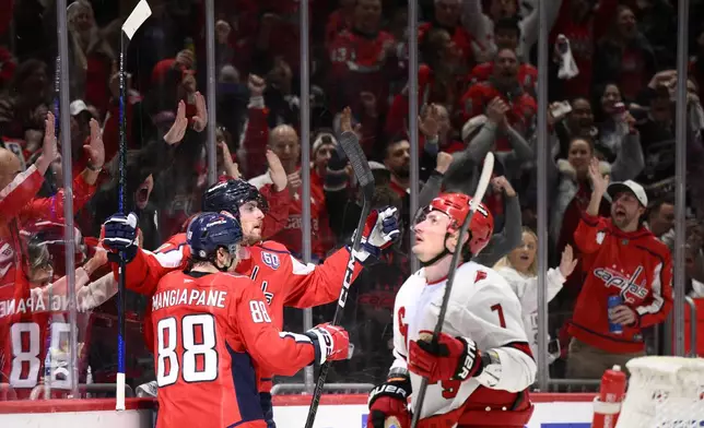 Washington Capitals left wing Pierre-Luc Dubois, center, celebrates his goal with left wing Andrew Mangiapane (88) next to Carolina Hurricanes defenseman Dmitry Orlov (7) during the first period of an NHL hockey game, Thursday, April 10, 2025, in Washington. (AP Photo/Nick Wass)