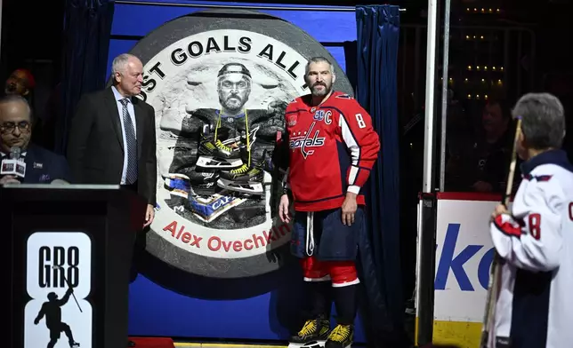 Washington Capitals left wing Alex Ovechkin (8) stands next to one of his gifts as he takes part in a pre-game ceremony to honor him for scoring 895 career NHL goals before an NHL hockey game against the Carolina Hurricanes, Thursday, April 10, 2025, in Washington. (AP Photo/Nick Wass)
