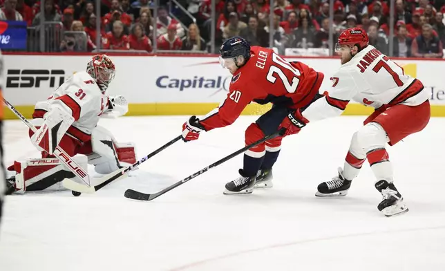 Washington Capitals center Lars Eller (20) tries to get the puck past Carolina Hurricanes goaltender Frederik Andersen (31) and Mark Jankowski (77) during the first period of an NHL hockey game, Thursday, April 10, 2025, in Washington. (AP Photo/Nick Wass)