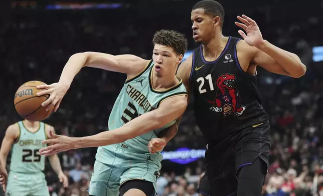 Charlotte Hornets' Tidjane Salaun (31) makes a pass as Toronto Raptors' Orlando Robinson (21) defends during the first half of an NBA basketball game in Toronto on Wednesday, April 9, 2025. (Frank Gunn/The Canadian Press via AP)