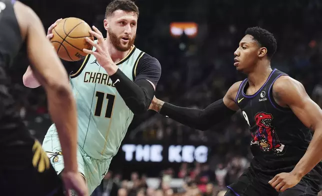 Charlotte Hornets' Jusuf Nurkic (11) drives as Toronto Raptors' RJ Barrett (9) defends during first half NBA basketball action in Toronto on Wednesday, April 9, 2025. (Frank Gunn/The Canadian Press via AP)