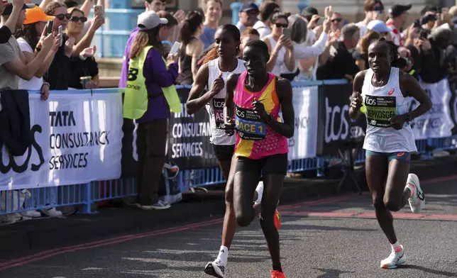 Ethiopia's Tigst Assefa, left, and Kenya's Joyciline Jepkosgei, right, compete in the women's elite race crossing Tower Bridge during the TCS London Marathon, Sunday April 27, 2025. (Jonathan Brady/PA via AP)