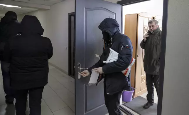 FILE - Police carry documents and computers from the office of the Belarusian Association of Journalists as Andrei Bastunets, the head the association, right, looks on in Minsk, Belarus, on Feb. 16, 2021. (AP Photo, File)