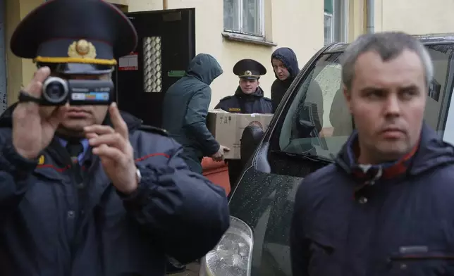 FILE - Belarusian Interior Ministry officer films journalists near the Belsat Channel during a search of the broadcaster’s office in Minsk, Belarus, on March 31, 2017. (AP Photo, File)