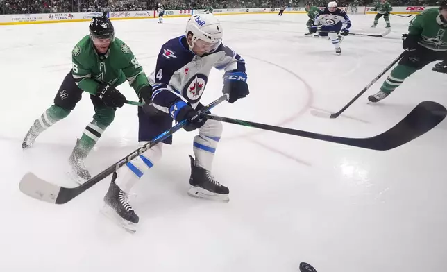 Winnipeg Jets defenseman Neal Pionk (4) and Dallas Stars right wing Mikko Rantanen (96) compete for the puck during the first period of an NHL hockey game Thursday, April 10, 2025, in Dallas. (AP Photo/Julio Cortez)