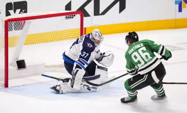 Winnipeg Jets goaltender Connor Hellebuyck (37) blocks a shot by Dallas Stars right wing Mikko Rantanen (96) during the third period of an NHL hockey game Thursday, April 10, 2025, in Dallas. (AP Photo/Julio Cortez)