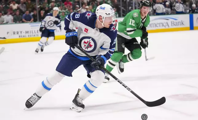 Winnipeg Jets center Jaret Anderson-Dolan (28) skates with the puck in front of Dallas Stars center Oskar Back (10) during the first period of an NHL hockey game Thursday, April 10, 2025, in Dallas. (AP Photo/Julio Cortez)