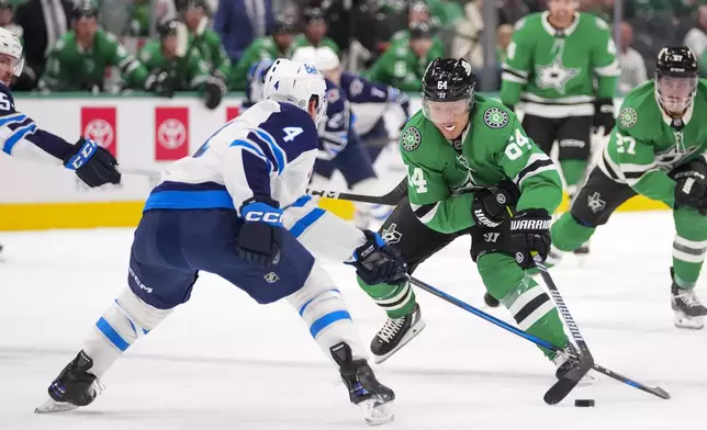 Dallas Stars center Mikael Granlund (64) attacks against Winnipeg Jets defenseman Neal Pionk (4) during the first period of an NHL hockey game Thursday, April 10, 2025, in Dallas. (AP Photo/Julio Cortez)