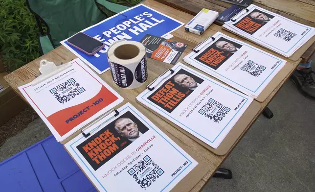 Flyers calling for the defeat of Sen. Thom Tillis, R-N.C., sit on a table outside a town hall with Sen. Chris Murphy, D-Conn., and Rep. Maxwell Frost, D-Fla., in Saxapahaw, N.C., Thursday, April 24, 2025. (AP Photo/Allen G. Breed)