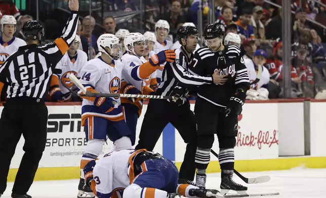 New Jersey Devils center Paul Cotter (47) stands over New York Islanders defenseman Adam Pelech (3) after being called for a penalty in the second period of an NHL hockey game Sunday, April 13, 2025, in Newark, N.J. (AP Photo/Adam Hunger)