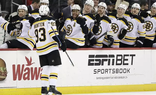Boston Bruins center Fraser Minten (93) celebrates with teammates after scoring a goal in the third period of an NHL hockey game against the New Jersey Devils Tuesday, April 8, 2025, in Newark, N.J. (AP Photo/Adam Hunger)
