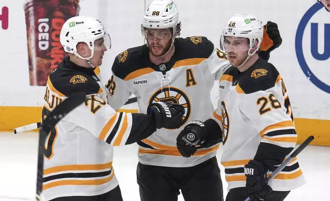 Boston Bruins' Elias Lindholm (28) celebrates his goal with David Pastrnak (88) and Henri Jokiharju during the first period of an NHL hockey game against the Pittsburgh Penguins in Pittsburgh, Sunday, April 13, 2025. (AP Photo/Gene J. Puskar)