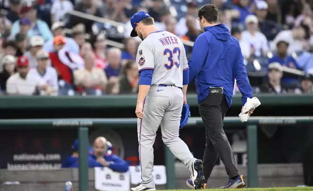 New York Mets relief pitcher A.J. Minter (33) leaves a baseball game with a trainer during the eighth inning against the Washington Nationals, Saturday, April 26, 2025, in Washington. (AP Photo/Nick Wass)