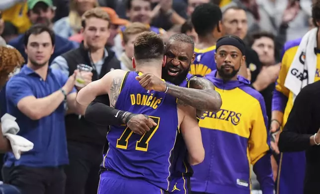 Los Angeles Lakers' Luka Doncic (77) and LeBron James, center, right, hug and celebrate late in the second half of an NBA basketball game against the Dallas Mavericks in Dallas, Wednesday, April 9, 2025. (AP Photo/LM Otero)