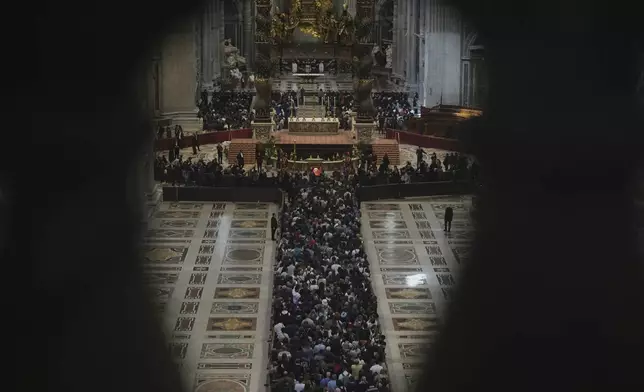 Balcony columns frame the queue of people lining up to pay their respects to Pope Francis lying in state, inside St. Peter's Basilica, at the Vatican, Friday, April 25, 2025. (AP Photo/Andrew Medichini)