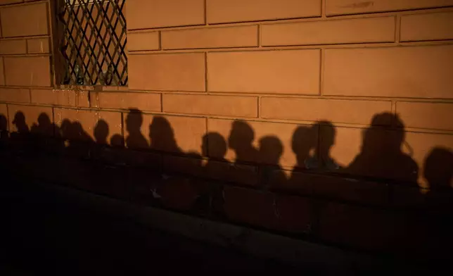 People stand in line as they wait to enter St. Peter's Basilica to pay their respects to Pope Francis lying in state, at the Vatican, Friday, April 25, 2025. (AP Photo/Emilio Morenatti)
