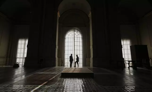Members of security are silhouetted by the windows of the balcony of St. Peter's Basilica, ahead of the arrival of the body of Pope Francis inside the basilica, where he will lie in state for three days, at the Vatican, Wednesday, April 23, 2025. (AP Photo/Andrew Medichini, Pool)