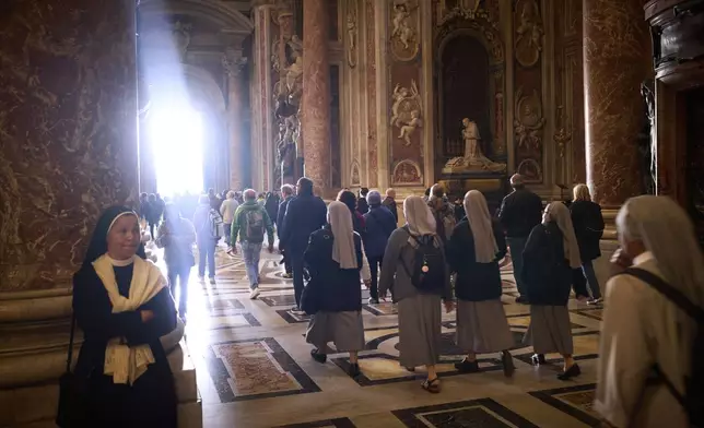 People walk at St. Peter's Basilica where Pope Francis lying in state, at the Vatican, Friday, April 25, 2025. (AP Photo/Emilio Morenatti)