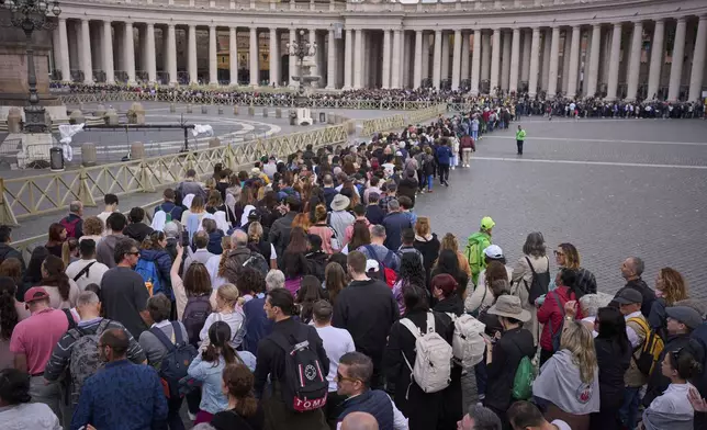 People stand in line as they wait to enter St. Peter's Basilica to pay their respects to Pope Francis lying in state, at the Vatican, Friday, April 25, 2025. (AP Photo/Emilio Morenatti)