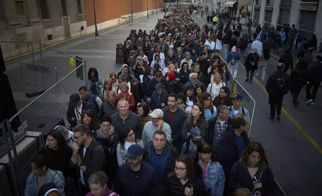 People stand in line as they wait to enter St. Peter's Basilica to pay their respects to Pope Francis lying in state, at the Vatican, Friday, April 25, 2025. (AP Photo/Emilio Morenatti)