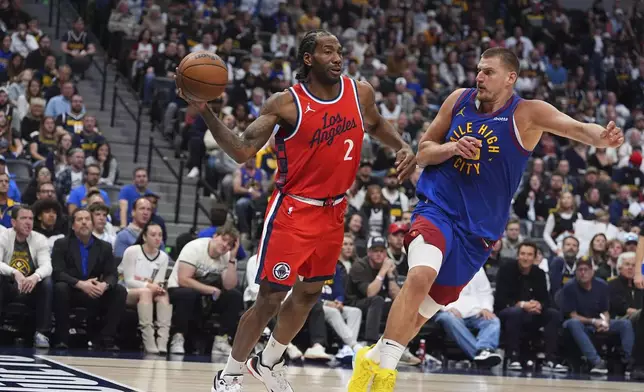 Los Angeles Clippers forward Kawhi Leonard, left, passes the ball as Denver Nuggets center Nikola Jokic defends in the second half of Game 1 of an NBA first-round playoff series Saturday, April 19, 2025, in Denver. (AP Photo/David Zalubowski)